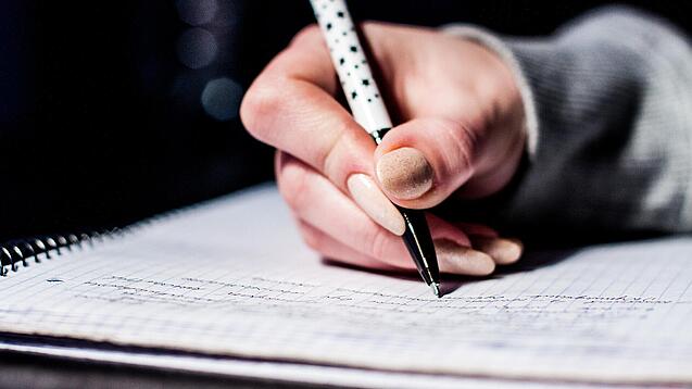 Die Hand einer Schülerin mit Stift und Block.