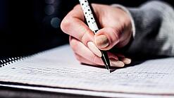 Die Hand einer Schülerin mit Stift und Block.