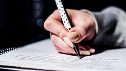 Die Hand einer Schülerin mit Stift und Block.