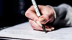 Die Hand einer Schülerin mit Stift und Block.