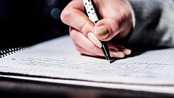 Die Hand einer Schülerin mit Stift und Block.