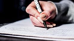 Die Hand einer Schülerin mit Stift und Block.