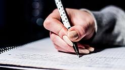 Die Hand einer Schülerin mit Stift und Block.