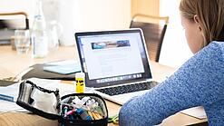 Mädchen sitzt vor einem Laptop.