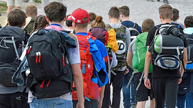 Gruppe von Schülerinnen und Schülern mit Rucksäcken auf einem Ausflug.