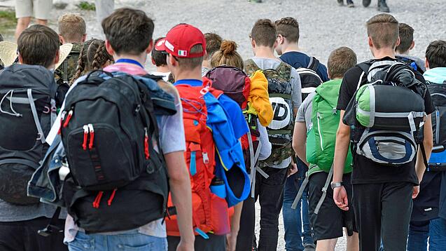 Gruppe von Schülerinnen und Schülern mit Rucksäcken auf einem Ausflug.