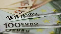 In einem Kreis liegen 100-Euro-, 50-Euro- und 20-Euro-Scheine aufgefächert.