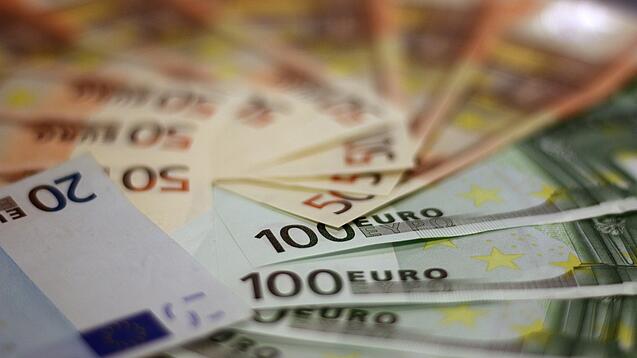 In einem Kreis liegen 100-Euro-, 50-Euro- und 20-Euro-Scheine aufgefächert.