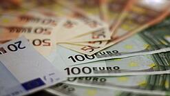 In einem Kreis liegen 100-Euro-, 50-Euro- und 20-Euro-Scheine aufgefächert.
