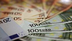 In einem Kreis liegen 100-Euro-, 50-Euro- und 20-Euro-Scheine aufgefächert.