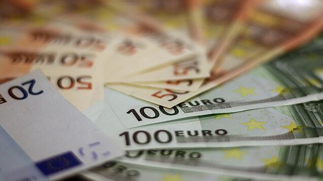 In einem Kreis liegen 100-Euro-, 50-Euro- und 20-Euro-Scheine aufgefächert.