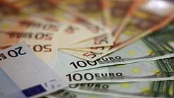 In einem Kreis liegen 100-Euro-, 50-Euro- und 20-Euro-Scheine aufgefächert.