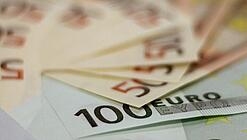 In einem Kreis liegen 100-Euro-, 50-Euro- und 20-Euro-Scheine aufgefächert.