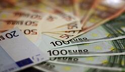 In einem Kreis liegen 100-Euro-, 50-Euro- und 20-Euro-Scheine aufgefächert.