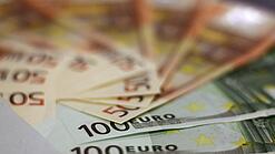 In einem Kreis liegen 100-Euro-, 50-Euro- und 20-Euro-Scheine aufgefächert.