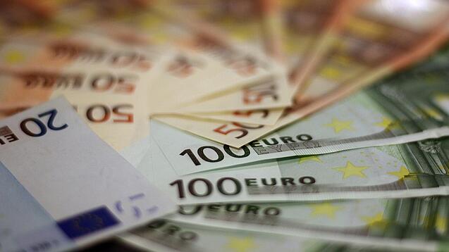 In einem Kreis liegen 100-Euro-, 50-Euro- und 20-Euro-Scheine aufgefächert.