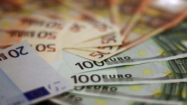 In einem Kreis liegen 100-Euro-, 50-Euro- und 20-Euro-Scheine aufgefächert.