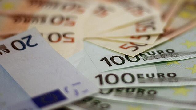 In einem Kreis liegen 100-Euro-, 50-Euro- und 20-Euro-Scheine aufgefächert.