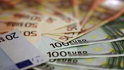 In einem Kreis liegen 100-Euro-, 50-Euro- und 20-Euro-Scheine aufgefächert.