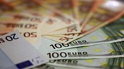 In einem Kreis liegen 100-Euro-, 50-Euro- und 20-Euro-Scheine aufgefächert.