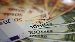 In einem Kreis liegen 100-Euro-, 50-Euro- und 20-Euro-Scheine aufgefächert.