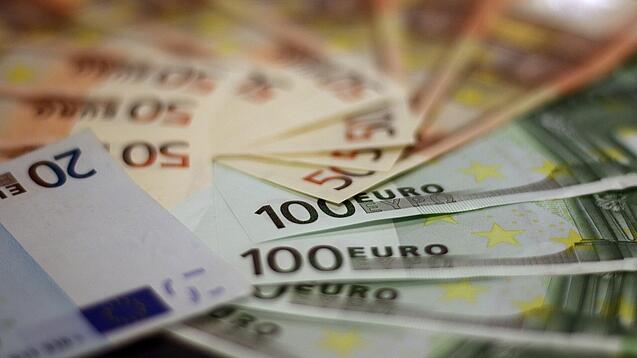 In einem Kreis liegen 100-Euro-, 50-Euro- und 20-Euro-Scheine aufgefächert.