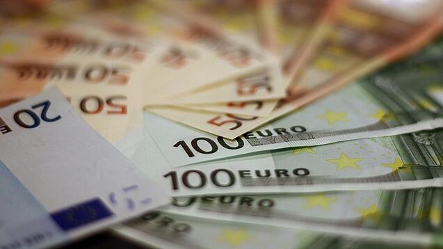 In einem Kreis liegen 100-Euro-, 50-Euro- und 20-Euro-Scheine aufgefächert.