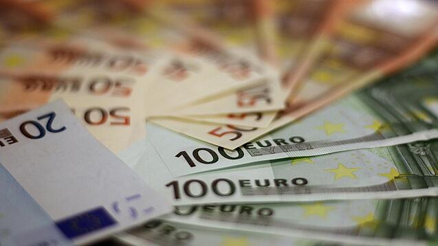 In einem Kreis liegen 100-Euro-, 50-Euro- und 20-Euro-Scheine aufgefächert.