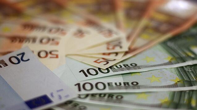 In einem Kreis liegen 100-Euro-, 50-Euro- und 20-Euro-Scheine aufgefächert.