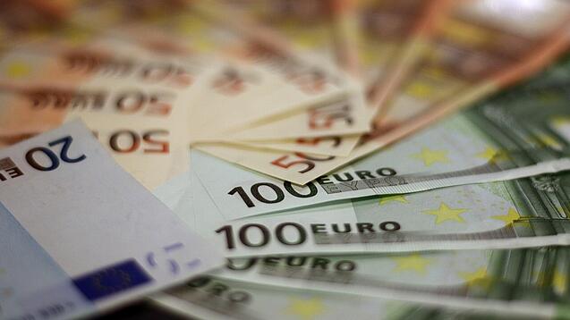 In einem Kreis liegen 100-Euro-, 50-Euro- und 20-Euro-Scheine aufgefächert.