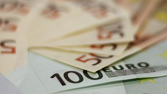 In einem Kreis liegen 100-Euro-, 50-Euro- und 20-Euro-Scheine aufgefächert.