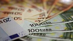 In einem Kreis liegen 100-Euro-, 50-Euro- und 20-Euro-Scheine aufgefächert.