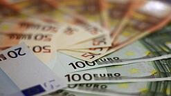 In einem Kreis liegen 100-Euro-, 50-Euro- und 20-Euro-Scheine aufgefächert.