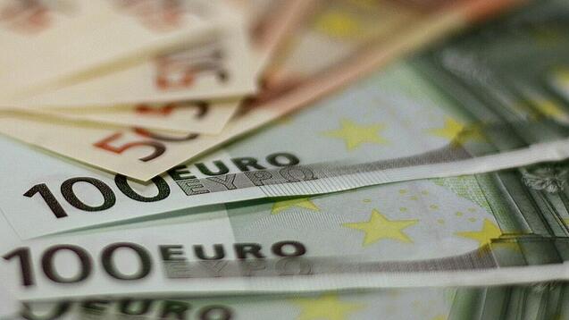 In einem Kreis liegen 100-Euro-, 50-Euro- und 20-Euro-Scheine aufgefächert.