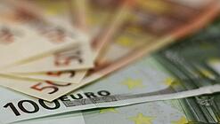 In einem Kreis liegen 100-Euro-, 50-Euro- und 20-Euro-Scheine aufgefächert.