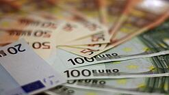 In einem Kreis liegen 100-Euro-, 50-Euro- und 20-Euro-Scheine aufgefächert.