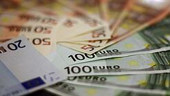 In einem Kreis liegen 100-Euro-, 50-Euro- und 20-Euro-Scheine aufgefächert.