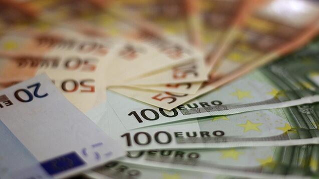 In einem Kreis liegen 100-Euro-, 50-Euro- und 20-Euro-Scheine aufgefächert.