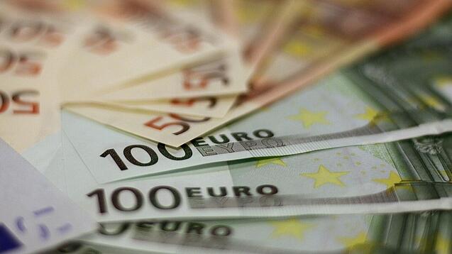 In einem Kreis liegen 100-Euro-, 50-Euro- und 20-Euro-Scheine aufgefächert.