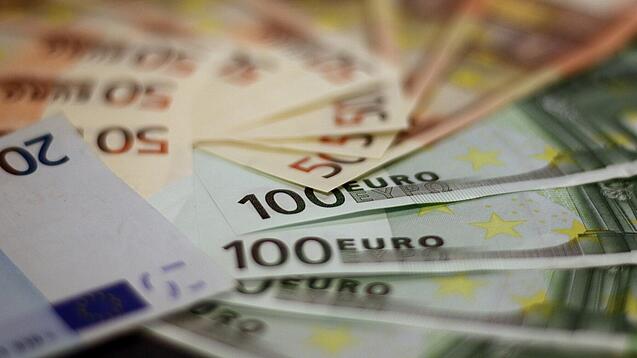 In einem Kreis liegen 100-Euro-, 50-Euro- und 20-Euro-Scheine aufgefächert.