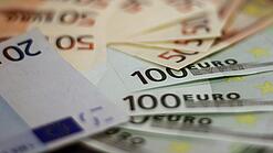 In einem Kreis liegen 100-Euro-, 50-Euro- und 20-Euro-Scheine aufgefächert.