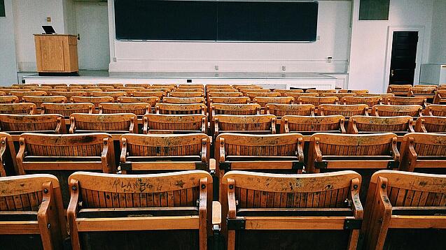 Ein leerer Hörsaal mit Bänken für die Studierenden.