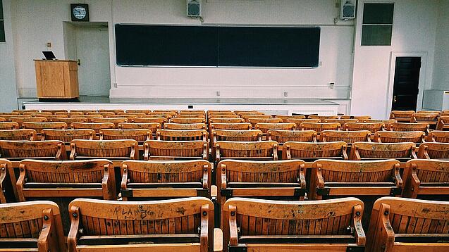 Ein leerer Hörsaal mit Bänken für die Studierenden.