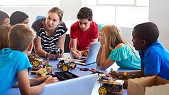 Eine Gruppe Kinder im Grundschulalter sitzt in einem Kreis und bekommt etwas erklärt.