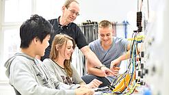 Gruppe junger Auszubildender und Ausbilder in einem Elektrobetrieb.