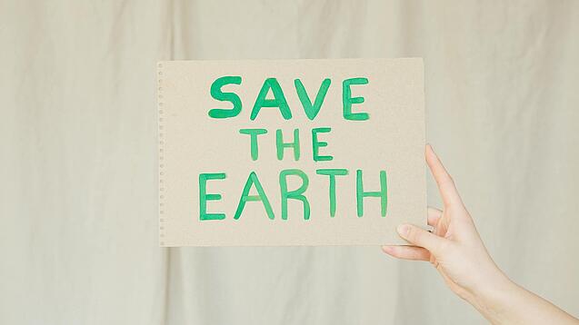 Ein Papier mit der Aufschrift „Save the earth“ wird hochgehalten.