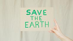 Ein Papier mit der Aufschrift „Save the earth“ wird hochgehalten.