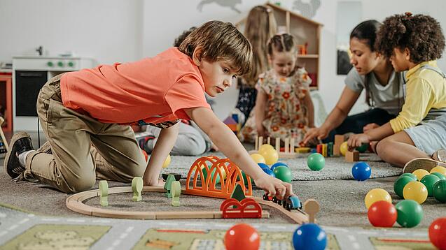 Mehrere Kinder spielen auf dem Boden.