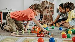 Mehrere Kinder spielen auf dem Boden.