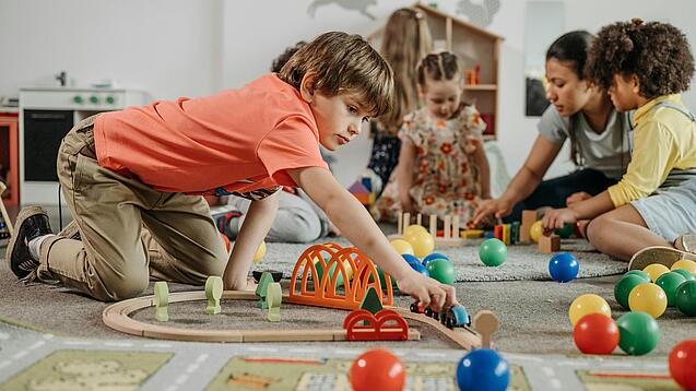 Mehrere Kinder spielen auf dem Boden.
